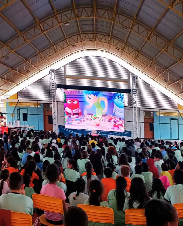 Crianças assistem a um filme no painel de LED dentro de um ginásio