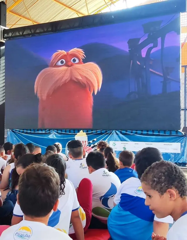 Crianças diante de um filme de animação no painel de LED